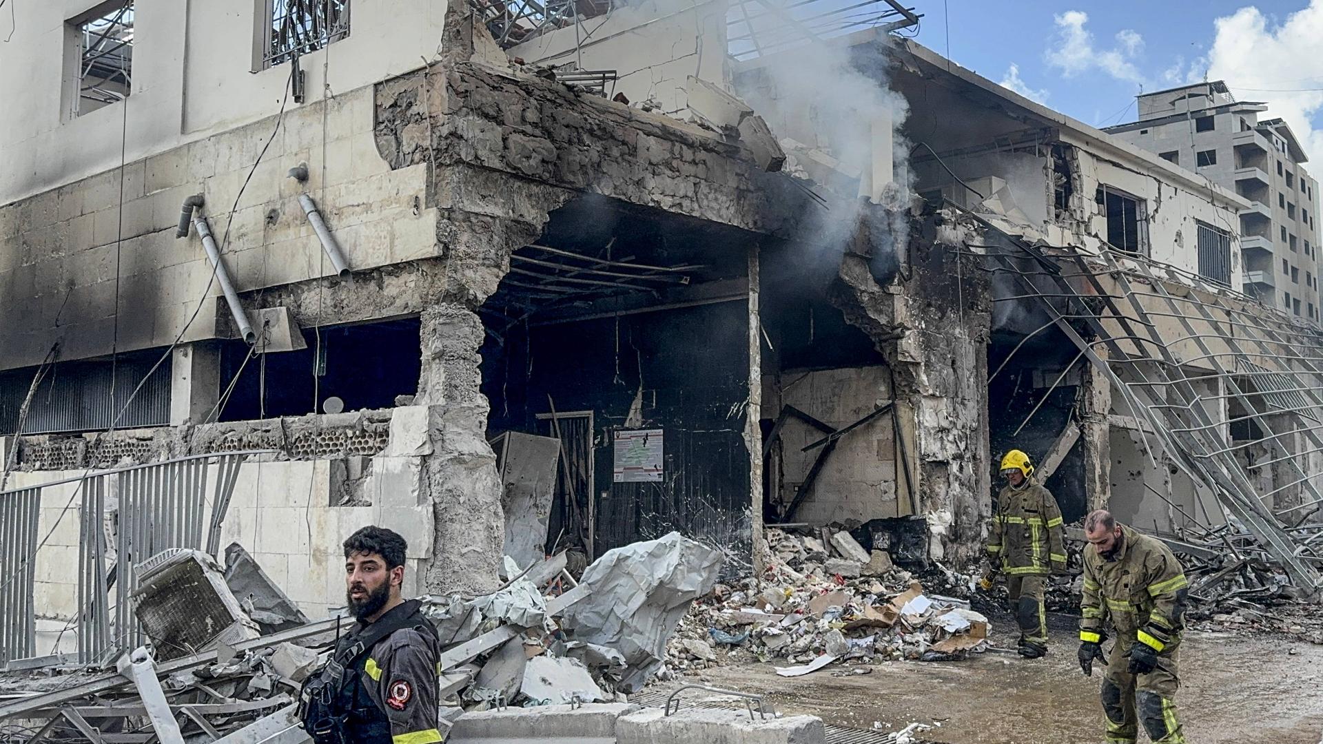 Bei dem Angriff in Nabatieh wurde nach Behördenangaben ein Regierungsgebäude zerstört. Vor dem zerstörten Haus sind drei Rettungskräfte zu sehen. 