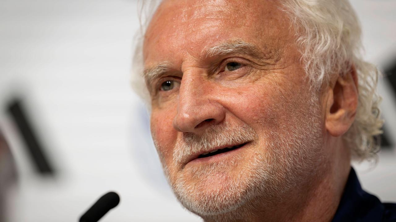 Rudi Völler, ein braungebrannter Mann mit weißen Haaren und Dreitagebart, im Halbprofil. Er spricht in ein Mikrofon. 