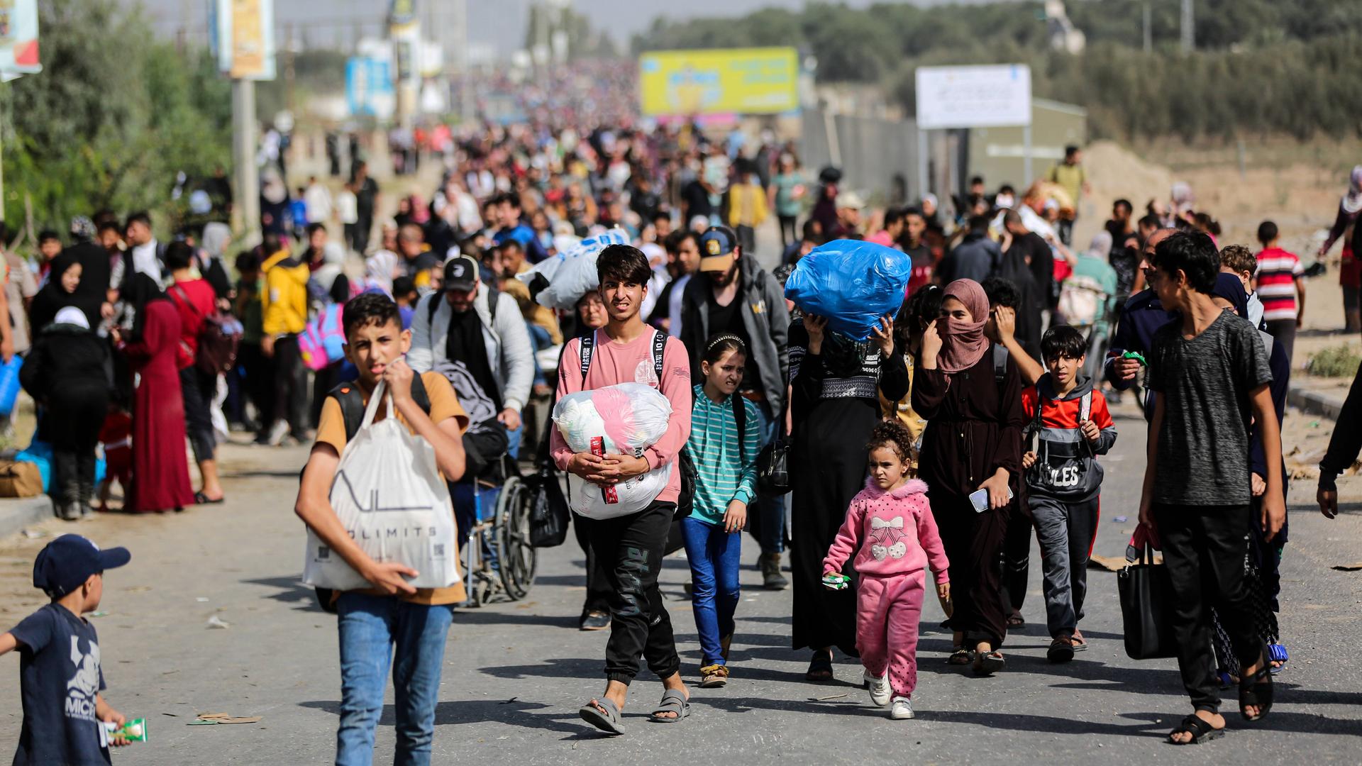 Viele Frauen und Kinder gehen im Gazastreifen mit Tüten und Säcken eine Straße entlang.