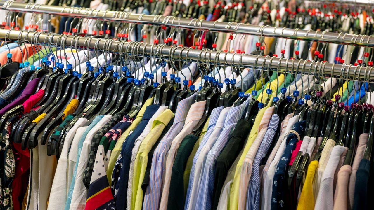 Verschiedenfarbige Hemden, Blusen und Westen werden im Einzelhandel als Massenware auf endlosen Kleiderstangen angeboten .