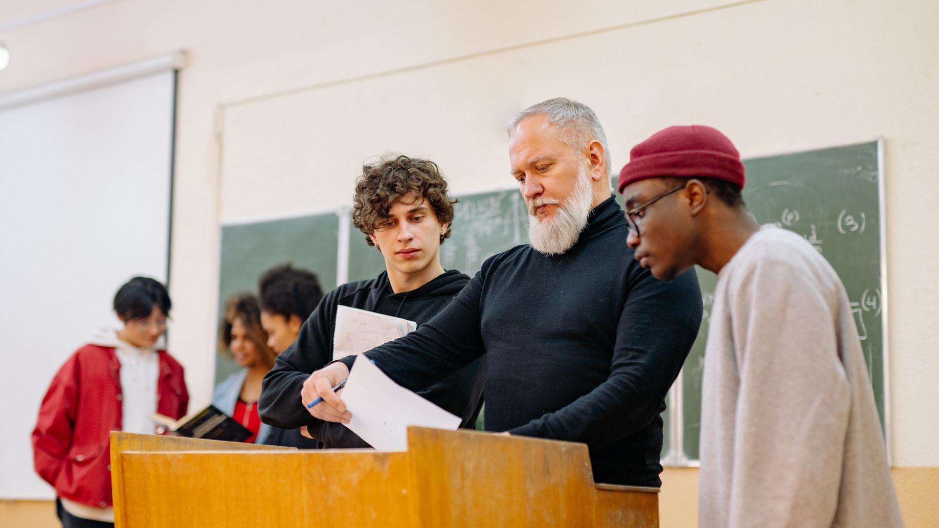 Studenten in der Uni lassen sich von Professor einen Ratschlag geben.