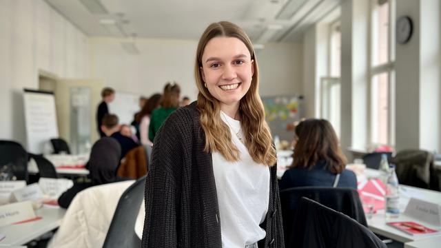 Melina steht in einem Seminarraum