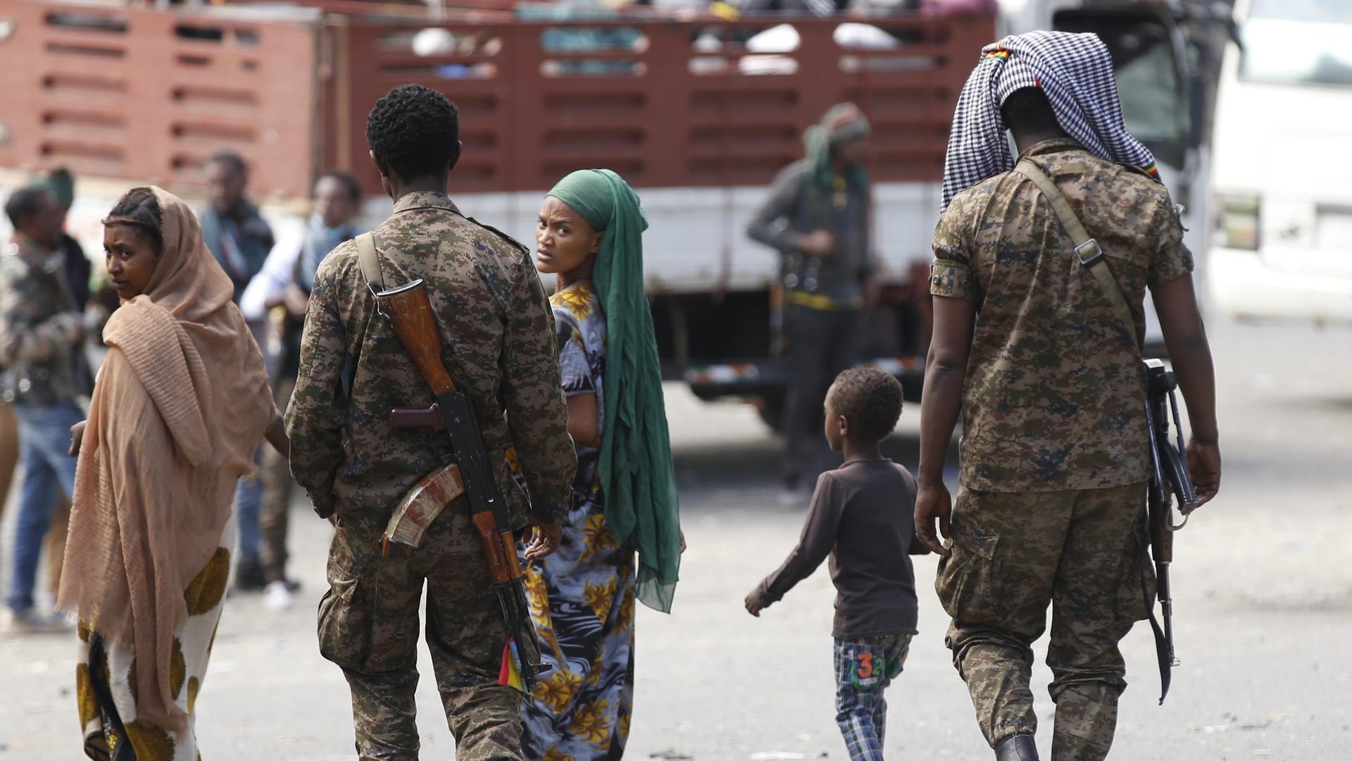 Äthiopische Militärangehörige laufen gemeinsam mit zwei Frauen und einem Kind eine Straße entlang. Eine der Frauen blickt sorgenvoll in die Kamera.
