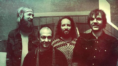 Die vier Mitglieder der Band stehen in einem Club eng beieinander.