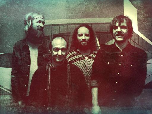 Die vier Mitglieder der Band stehen in einem Club eng beieinander.