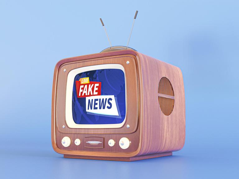Ein Röhrenfernseher, auf dem Bildschirm steht "Fake News".