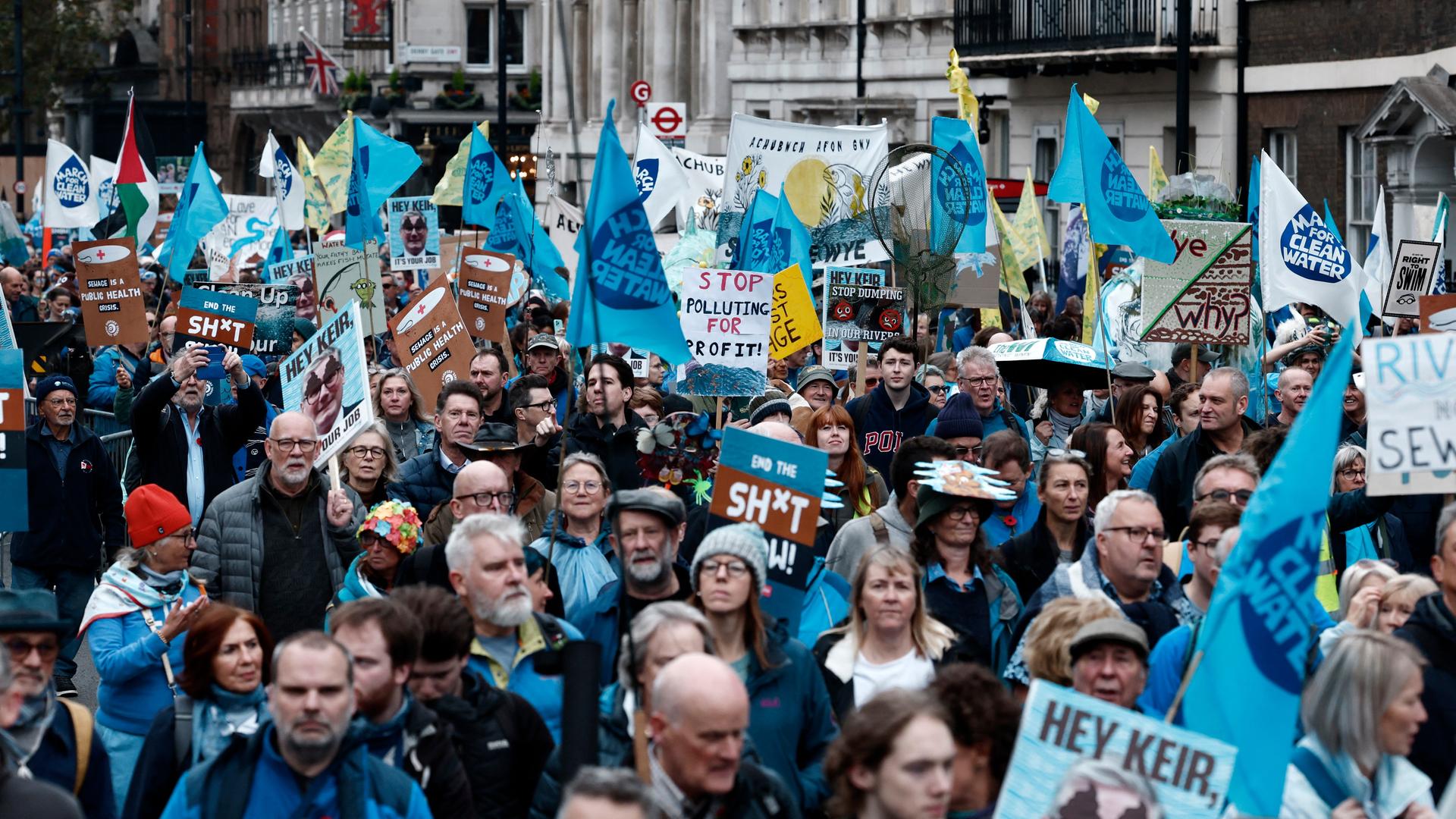 Menschen protestieren in London gegen Waserverschmutzung. Die Demosntranten halten blaue Plakate in die Höhe. Menschen protestieren in London gegen Waserverschmutzung. Die Demosntranten halten blaue Plakate in die Höhe.