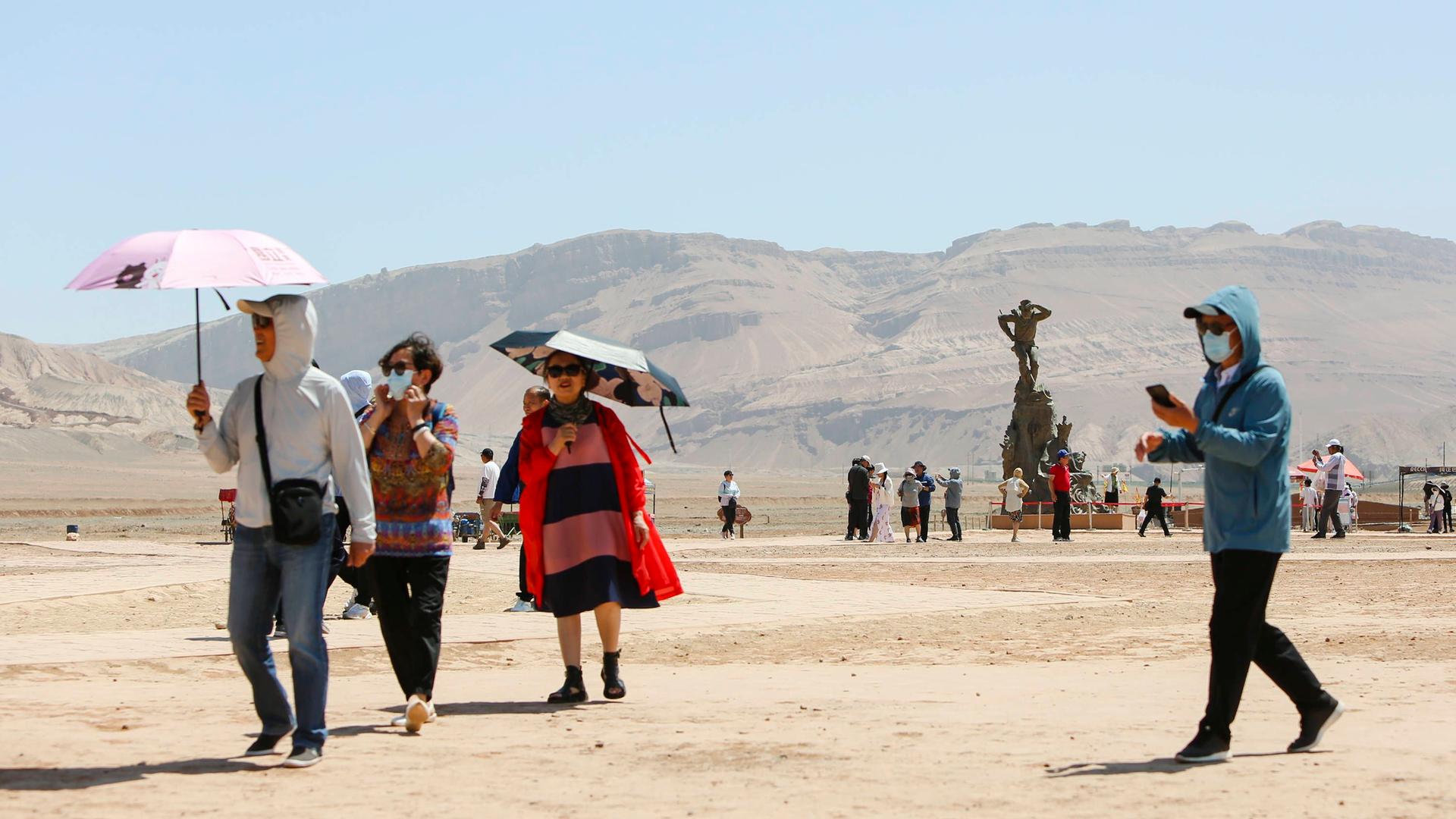 China, Tupan-Senke: Touristen schützen sich mit Schirmen vor der Hitze.