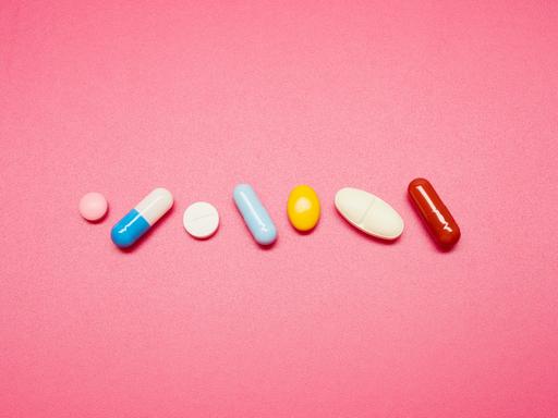 Bunte Pillen und Tabletten auf rosa farbigem Hintergrund.