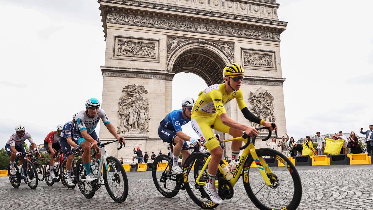 Eine Gruppe von Radsportlern fährt am Triumphbogen vorbei. Pogacar mit dem gelben Trikot im Vordergrund.