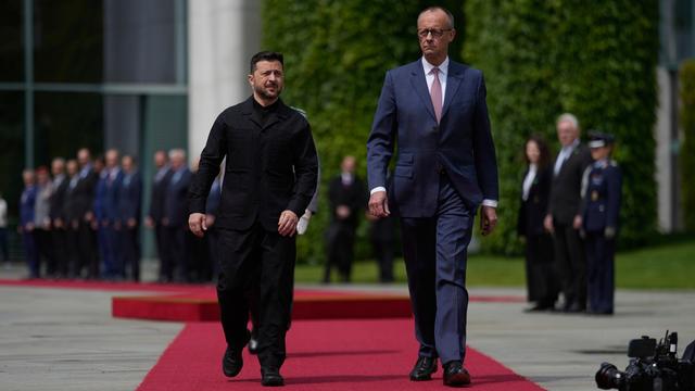 Der Präsident von der Ukraine Selenskyj und Bundes-Kanzler Merz gehen nebeneinander über den roten Teppich beim Empfang in Berlin.