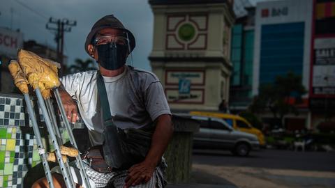 Ein Bewohner einer Leprakolonie sitzt mit einer Beinprothese an einer Kreuzung in Indonesien