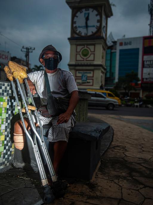 Ein Bewohner einer Leprakolonie sitzt mit einer Beinprothese an einer Kreuzung in Indonesien