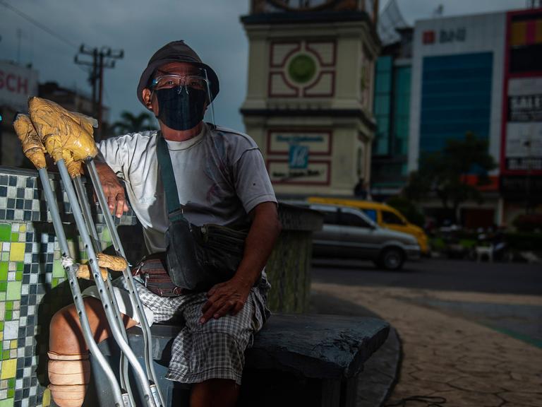 Ein Bewohner einer Leprakolonie sitzt mit einer Beinprothese an einer Kreuzung in Indonesien