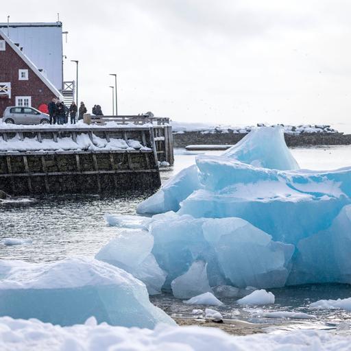Eisberge in Grönland und ein Haus im Hintergrund.