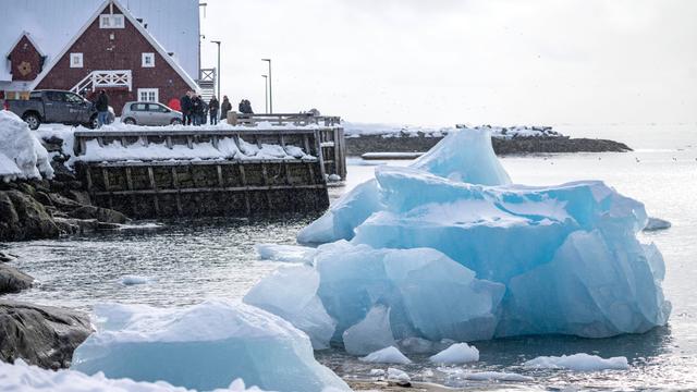 Eisberge in Grönland und ein Haus im Hintergrund.