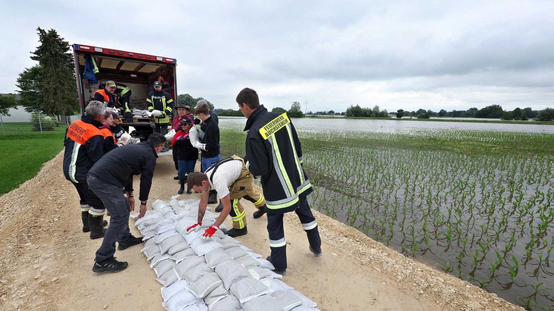 Das Bild zeigt Feuerwehrleute und freiwillige Helfer, die nahe Donauwörth nach einem Dammbruch einen zweiten Deich mit Sandsäcken befestigen. 
