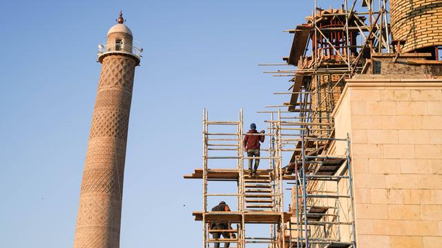 Auf dem Bild sieht man Arbeiter, die eine Moschee wieder aufbauen. 