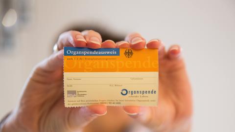 Eine Person hält einen Organspendeausweis in den Händen. 