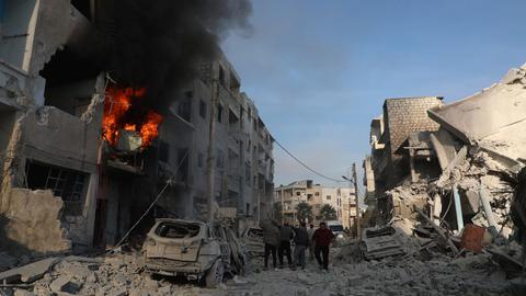 Syrien, Idlib: Dieses Foto der Weißhelme des syrischen Zivilschutzes, das anhand seines Inhalts und anderer AP-Berichte authentifiziert wurde, zeigt syrische Einwohner, die sich in der Nähe von zerstörten Gebäuden versammeln, nachdem syrische Regierungstruppen die Stadt Idlib angegriffen haben.