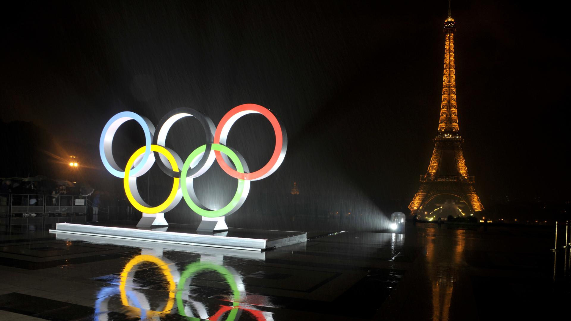 Die erleuchteten olympischen Ringe vor dem Eiffelturm Die erleuchteten olympischen Ringe vor dem Eiffelturm