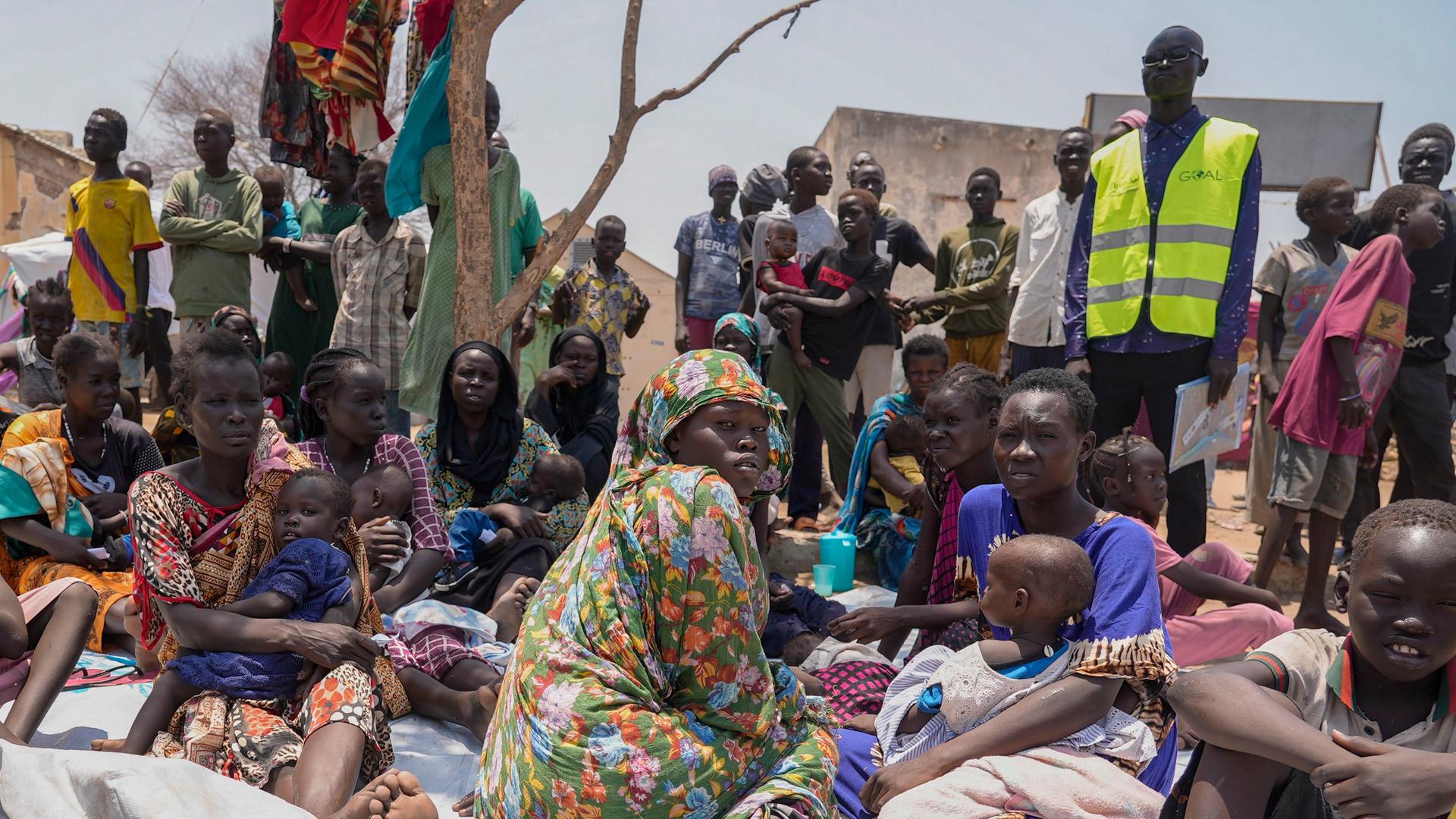 Südsudanesen, die aus dem Sudan geflohen sind, sitzen vor einer Ernährungsklinik in einem Transitzentrum.