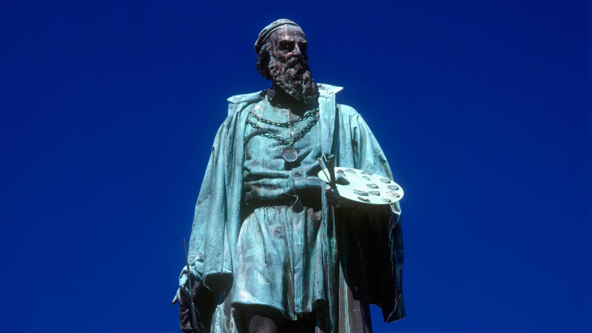 Das Denkmal zeigt den bärtigen Maler Tizian mit Pinsel und Farbpalette in der linken Hand.