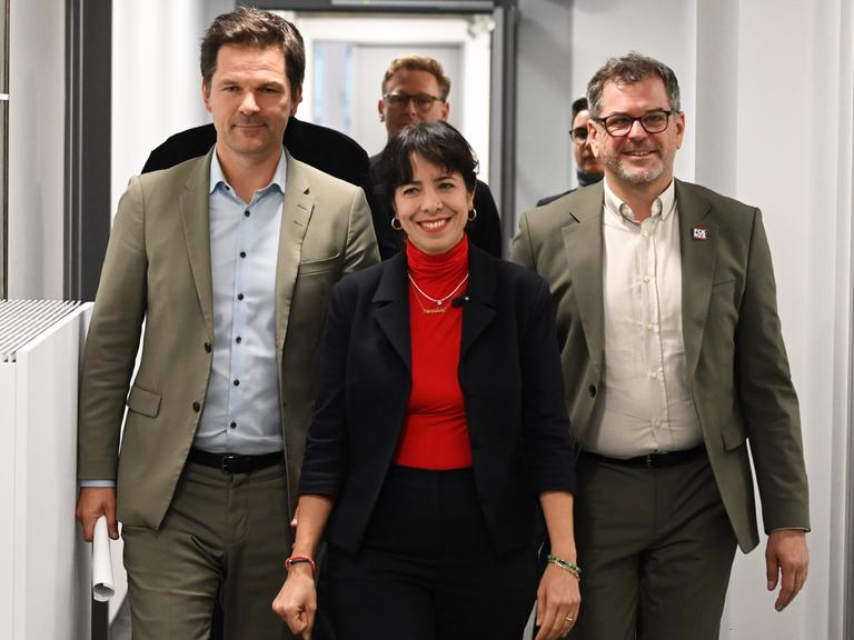 Werner Graf (Bündnis 90/Die Grünen), Elif Eralp (Die Linke) und Steffen Krach (SPD) (v.r.n.l) laufen nebeneinander durch einen Flur und lächeln dabei Werner Graf (Bündnis 90/Die Grünen), Elif Eralp (Die Linke) und Steffen Krach (SPD) (v.r.n.l) laufen nebeneinander durch einen Flur und lächeln dabei
