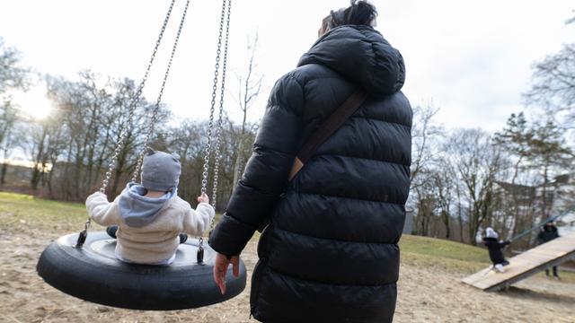 Mutter mit Kleinkind auf einem Spielplatz.