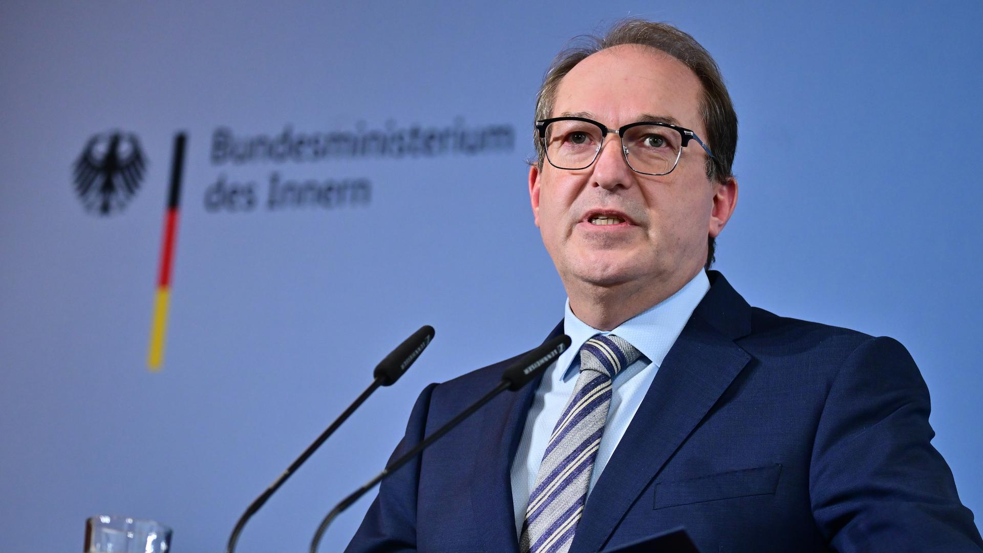 Dobrindt im dunklen Jackett spricht in zwei Mikrofone. An der blauen Wand dahinter der Schriftzug seines Ministeriums. 