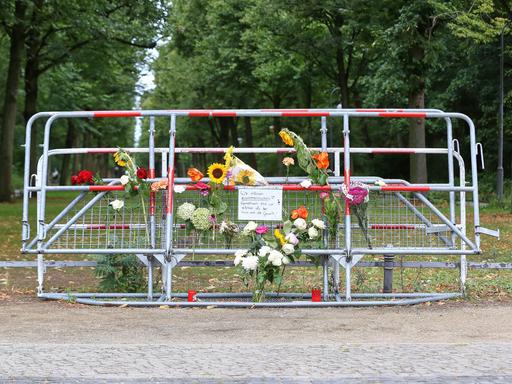 Am Tatort des CSD-Anschlags in Berlin haben Menschen an Absperrgittern Blumen niedergelegt, auf einem Schild steht "Wir müssen zusammenhalten. Gemeinsam sind wir stärker als der Hass und die Gewalt!"