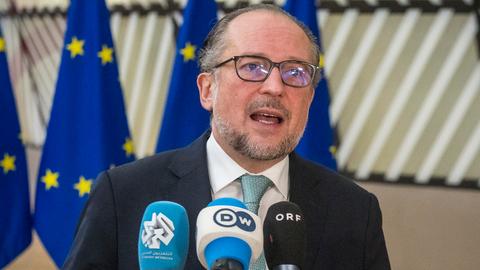 Der Österreichische Aussenminister Alexander Schallenberg steht vor drei EU-Flaggen und spricht in Mikrofone von Pressevertretern.