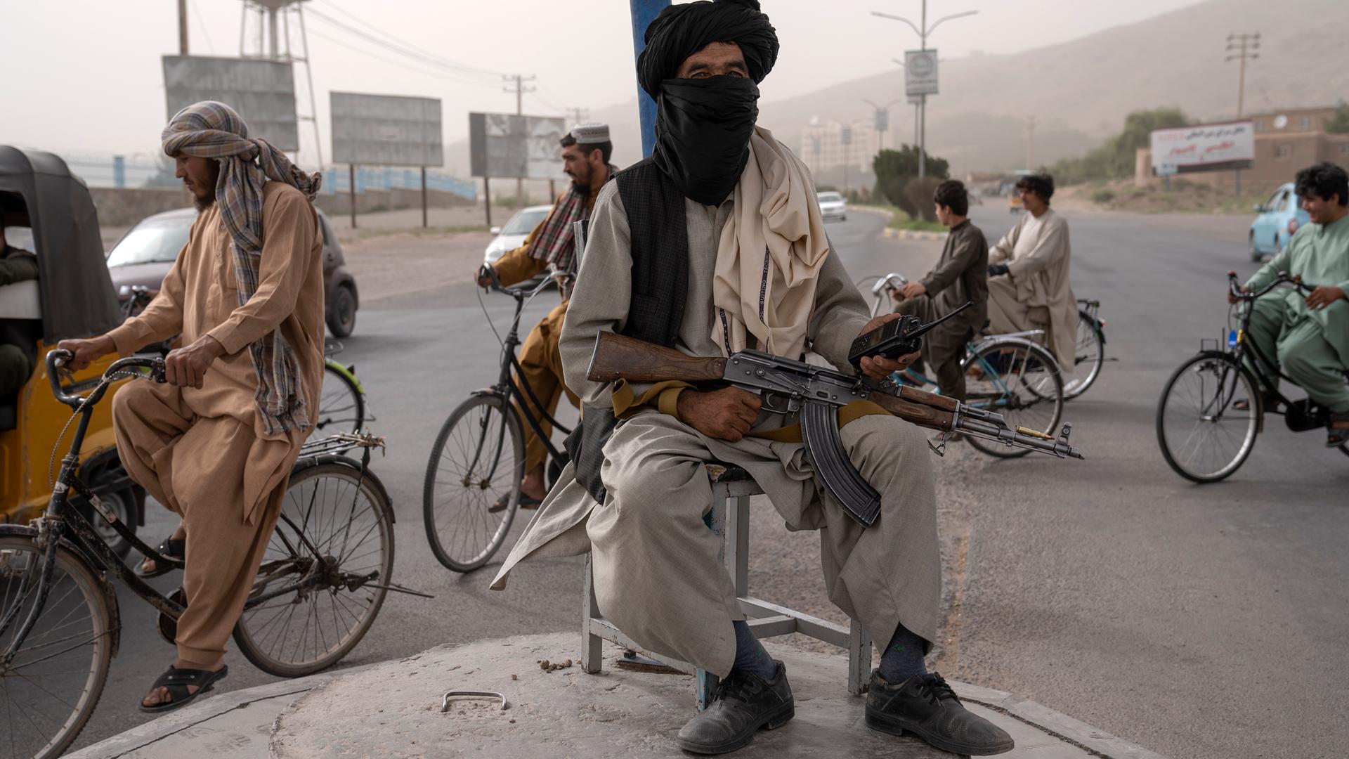 Ein bewaffneter Taliban-Kämpfer sitzt auf einer Erhebung in der Mitte eines Kreisverkehrs in Kabul.