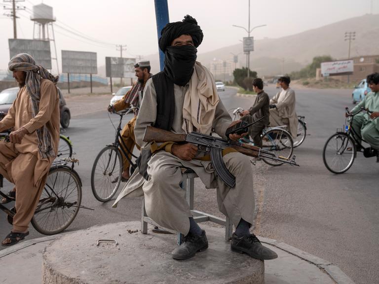 Ein bewaffneter Taliban-Kämpfer sitzt auf einer Erhebung in der Mitte eines Kreisverkehrs in Kabul.