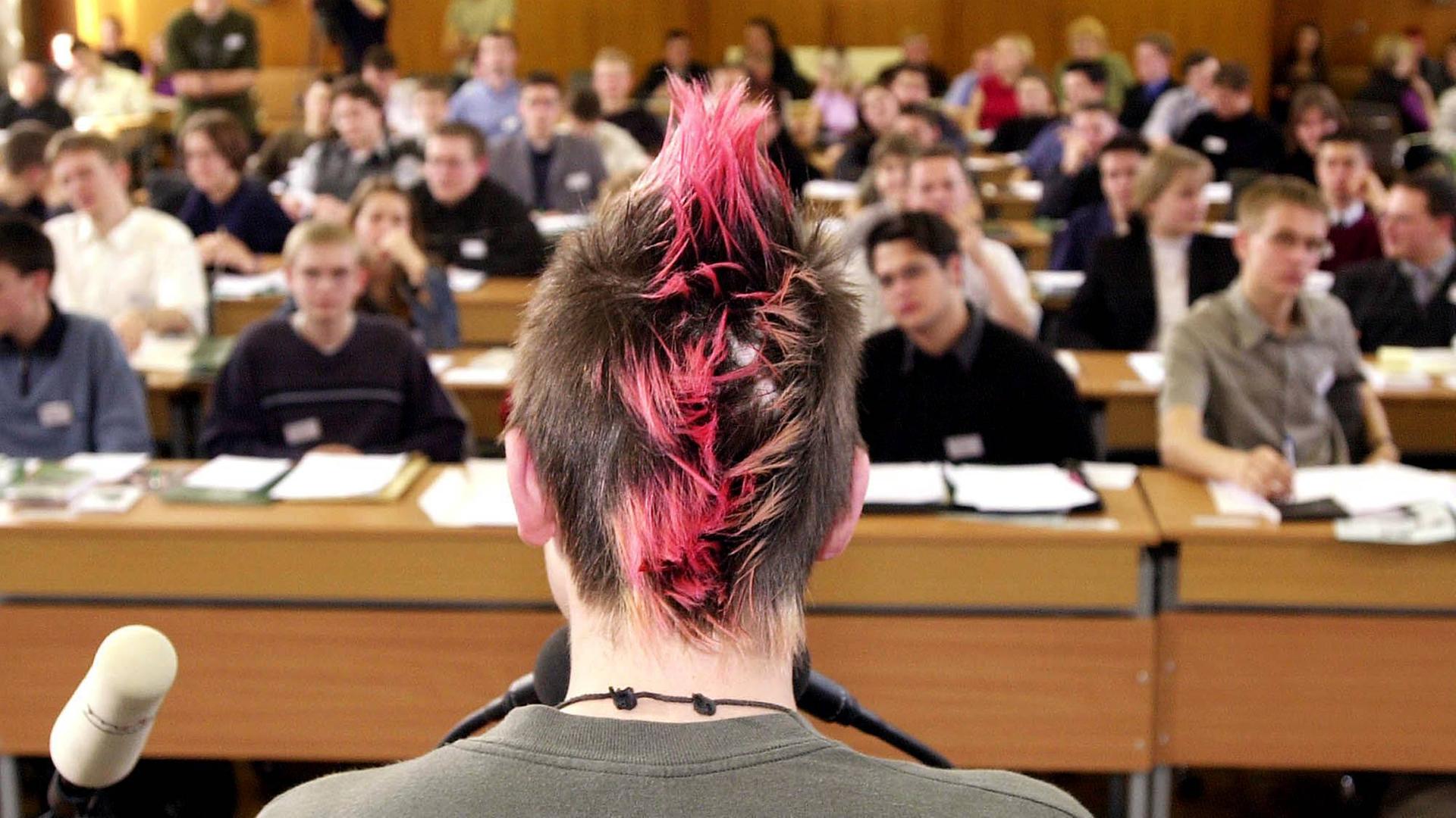 Ein Jugendlicher mit gefärbten aufgestellten Haaren ist von hinten zu sehen, während er eine Rede auf der Tagung des Jugendparlaments in Erfurt hält.