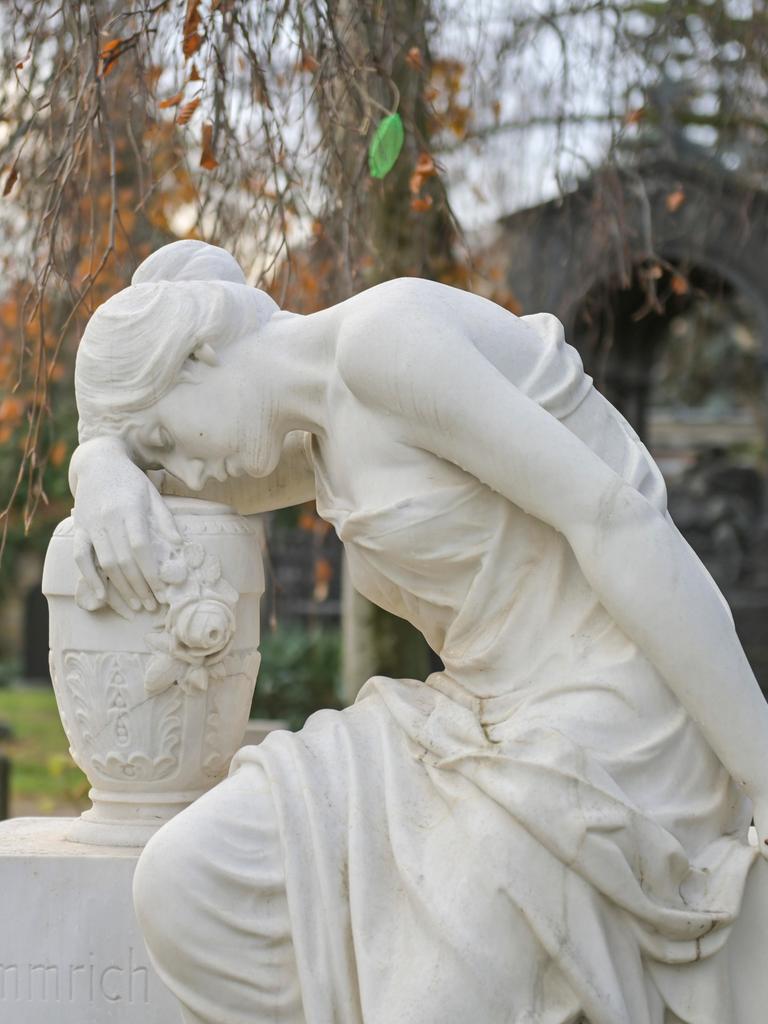 Die Skulptur auf dem Französischen Friedhof in Berlin zeigt eine sitzende Frauenfigur, die sich in Trauer versunken, mit geschlossenen Augen an eine neben ihr stehende Urne schmiegt und sich mit einer Hand an dem Stein festhält, auf dem sie sitzt. 