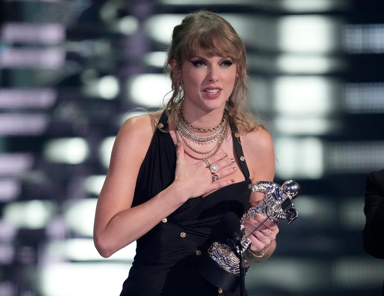 Die Musikerin Taylor Swift steht auf der Bühne, hält einen MTV Award in der Hand und macht eine Geste der Rührung.