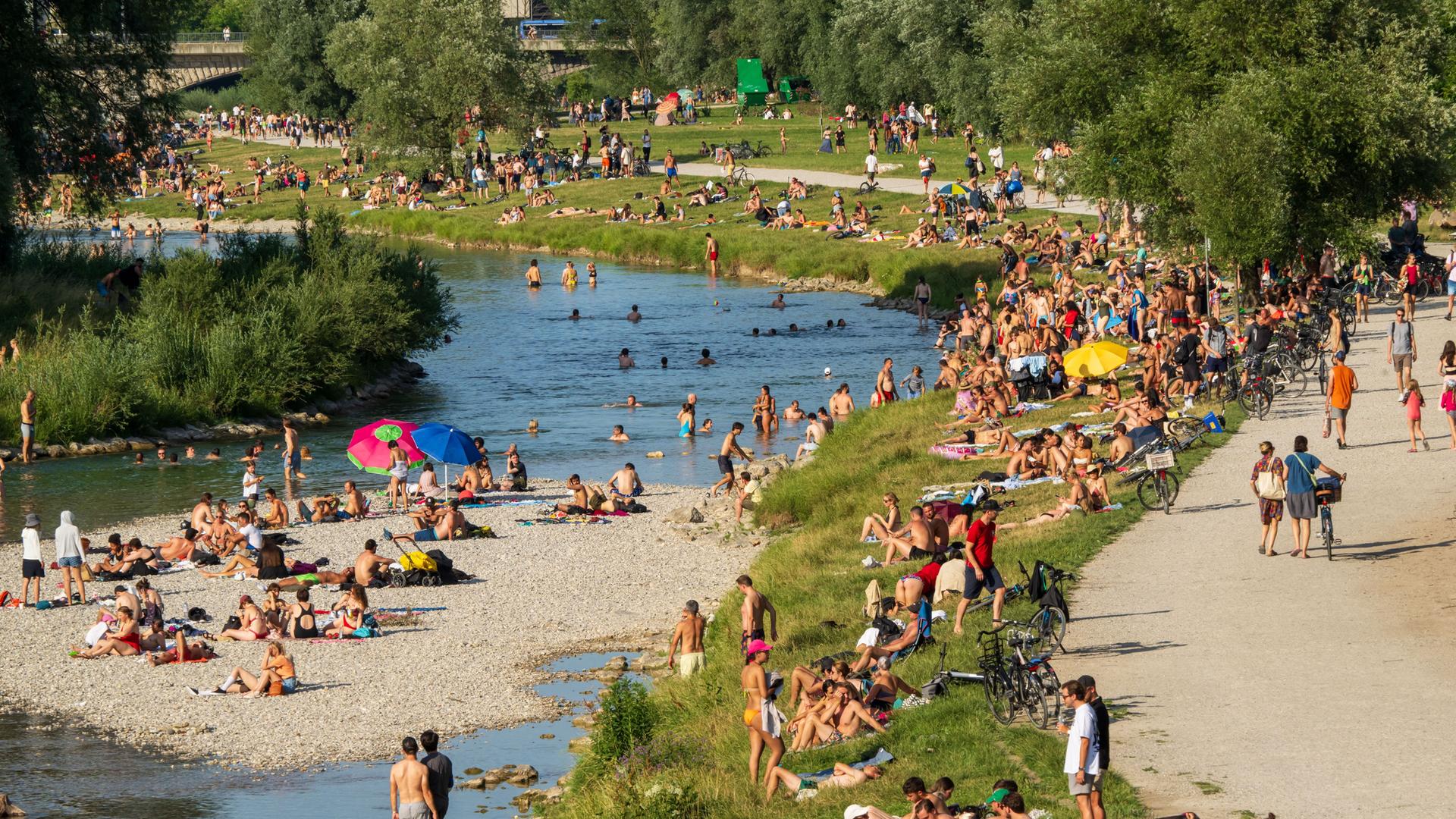 Zahlreiche Menschen suchen am Ufer und in der Isar Abkühlung von den hochsommerlichen Temperaturen.