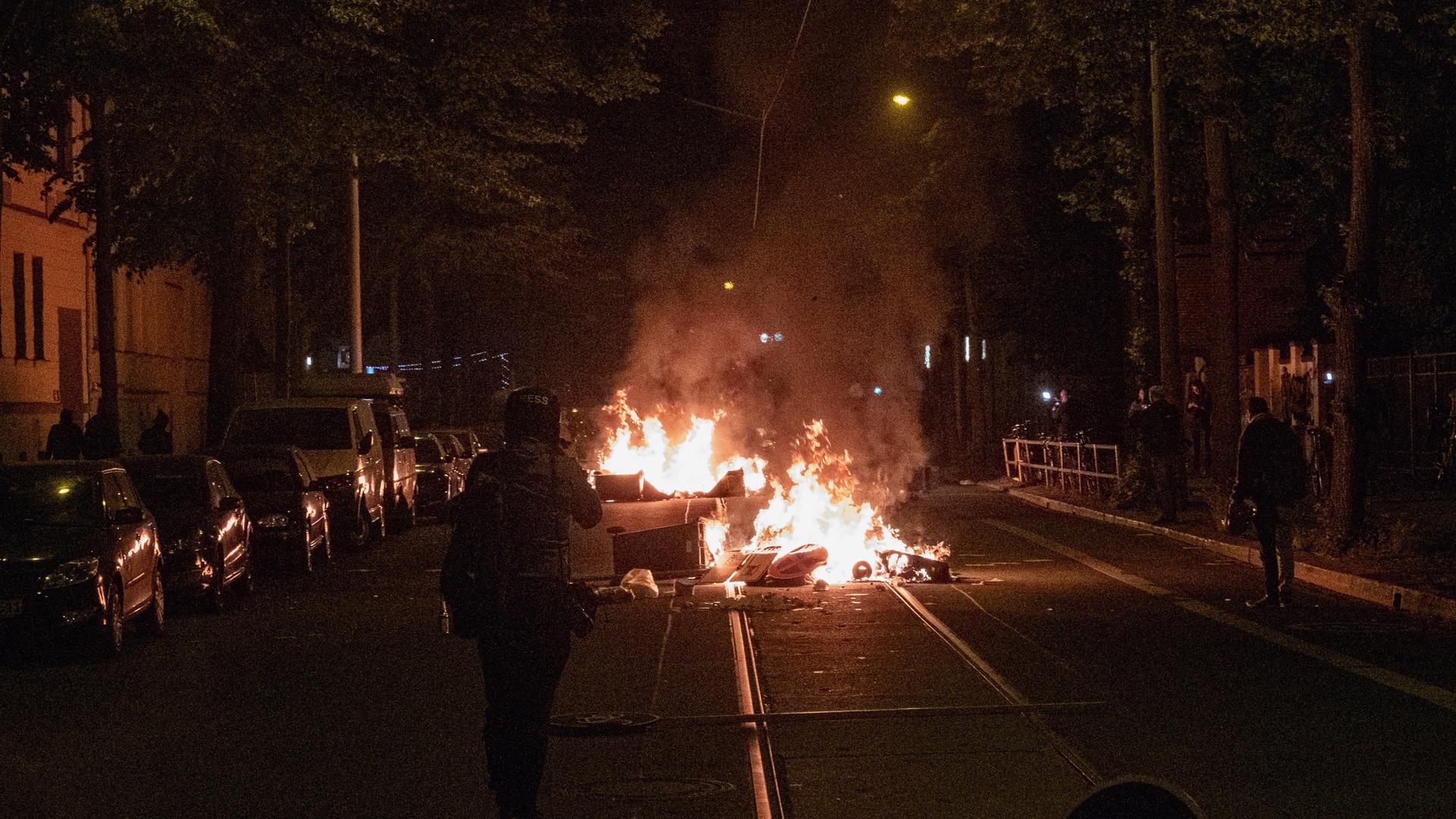 Am Vorabend des "Tag X" anlässlich des Antifa Ost Prozesses zogen mehrere Hundert Menschen aus der linksautonomen und linksextremen Szene durch den Leipziger Stadtteil Connewitz. Mülleimer brennen auf der Mitte einer Straße. 