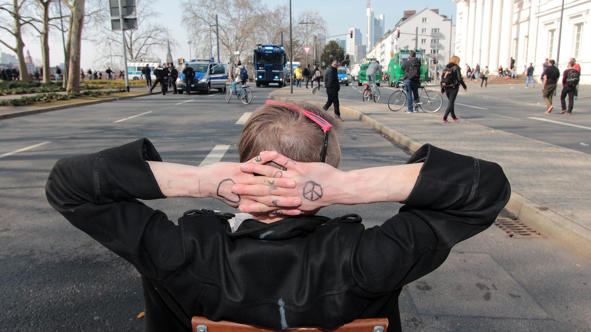 Ein Demonstrant lehnt sich zurück und faltet die Hände hinter dem Kopf während eine Straße abgeriegelt wird. 
