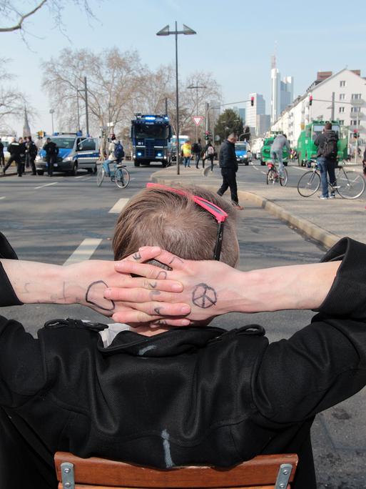 Ein Demonstrant lehnt sich zurück und faltet die Hände hinter dem Kopf während eine Straße abgeriegelt wird. 