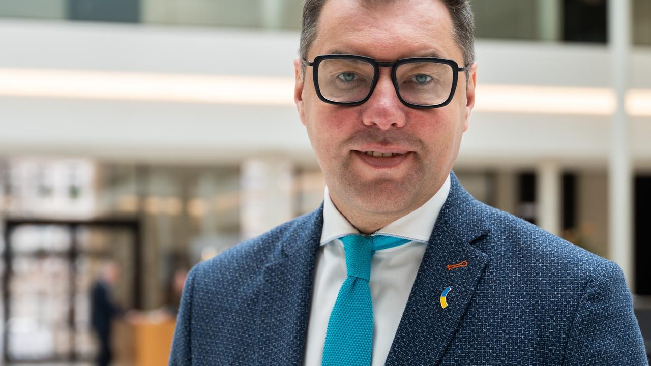 Oleksii Makeiev, ukrainischer Botschafter in Deutschland, steht im Niedersächsischen Landtag. Er trägt eine schwarze Brille, ein blaues Sakko mit weißem Hemd und hellblauer Krawatte. Am Revers steckt ein Pinn in den Farben der ukrainischen Flagge.