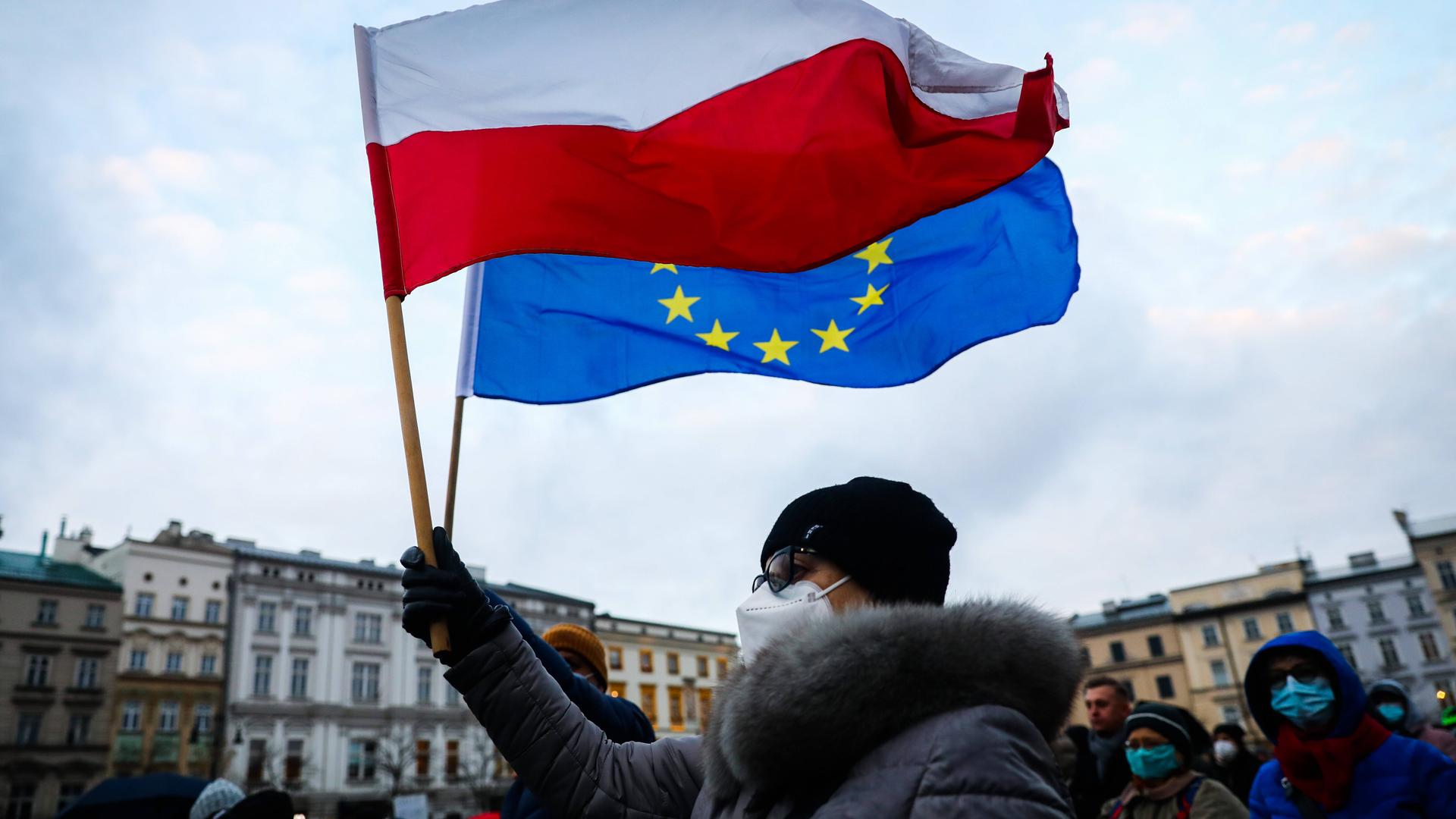 Eine Frau hält in Krakau in Polen bei Protesten gegen das geplante Mediengesetz eine polnische und eine EU-Flagge in der Hand 