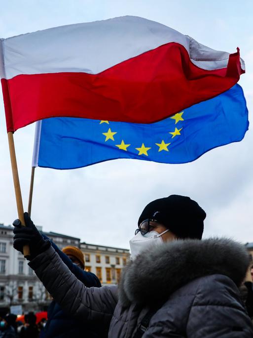 Eine Frau hält in Krakau in Polen bei Protesten gegen das geplante Mediengesetz eine polnische und eine EU-Flagge in der Hand 