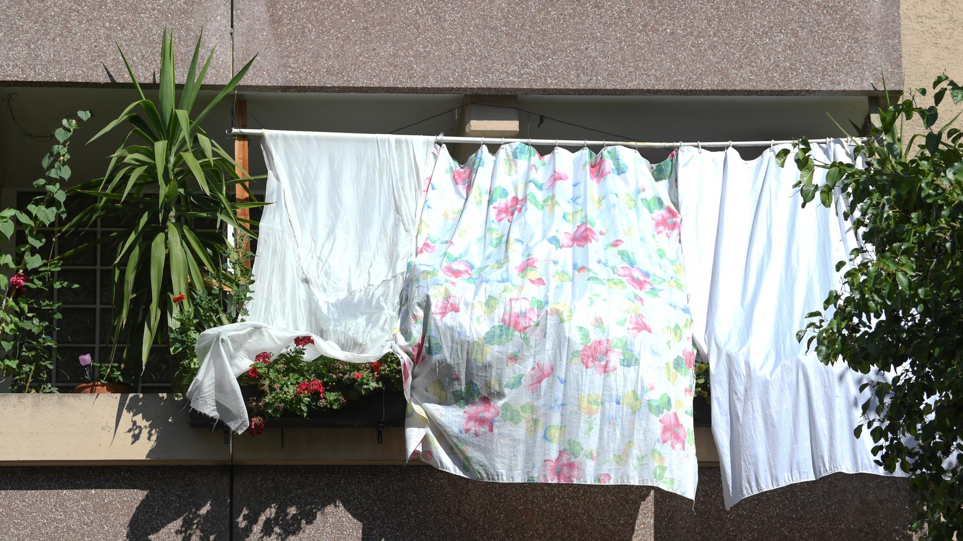 Mit auf dem Balkon gespannten Tüchern schützen Bewohner notdürftig ihre Wohnung  vor der heißen Sonne. 