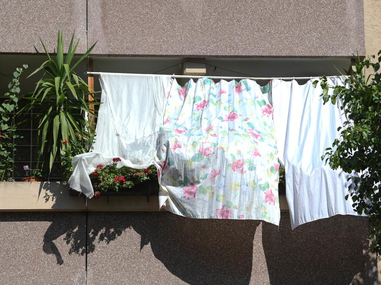 Mit auf dem Balkon gespannten Tüchern schützen Bewohner notdürftig ihre Wohnung  vor der heißen Sonne. 