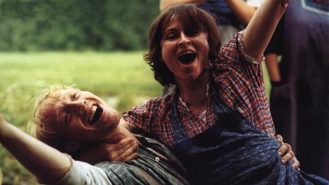 Sophie Rois lacht ausgelassen zusammen mit Simon Schwarz auf einem Feld in einer Szene des Filmes Siebtelbauern.