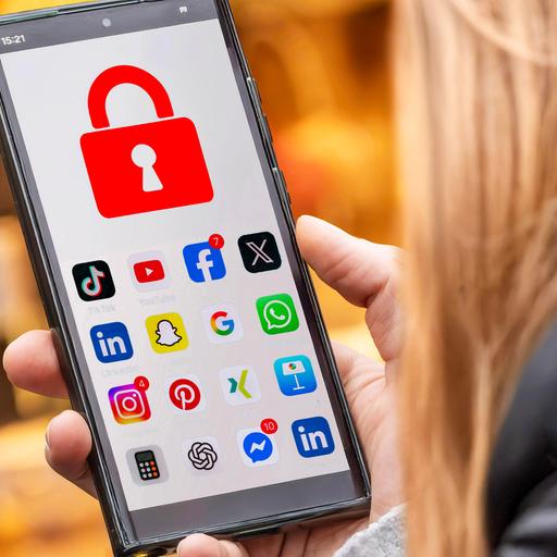 Symbolfoto: Schülerin mit Handy und Social Media Apps, die gesperrt sind
