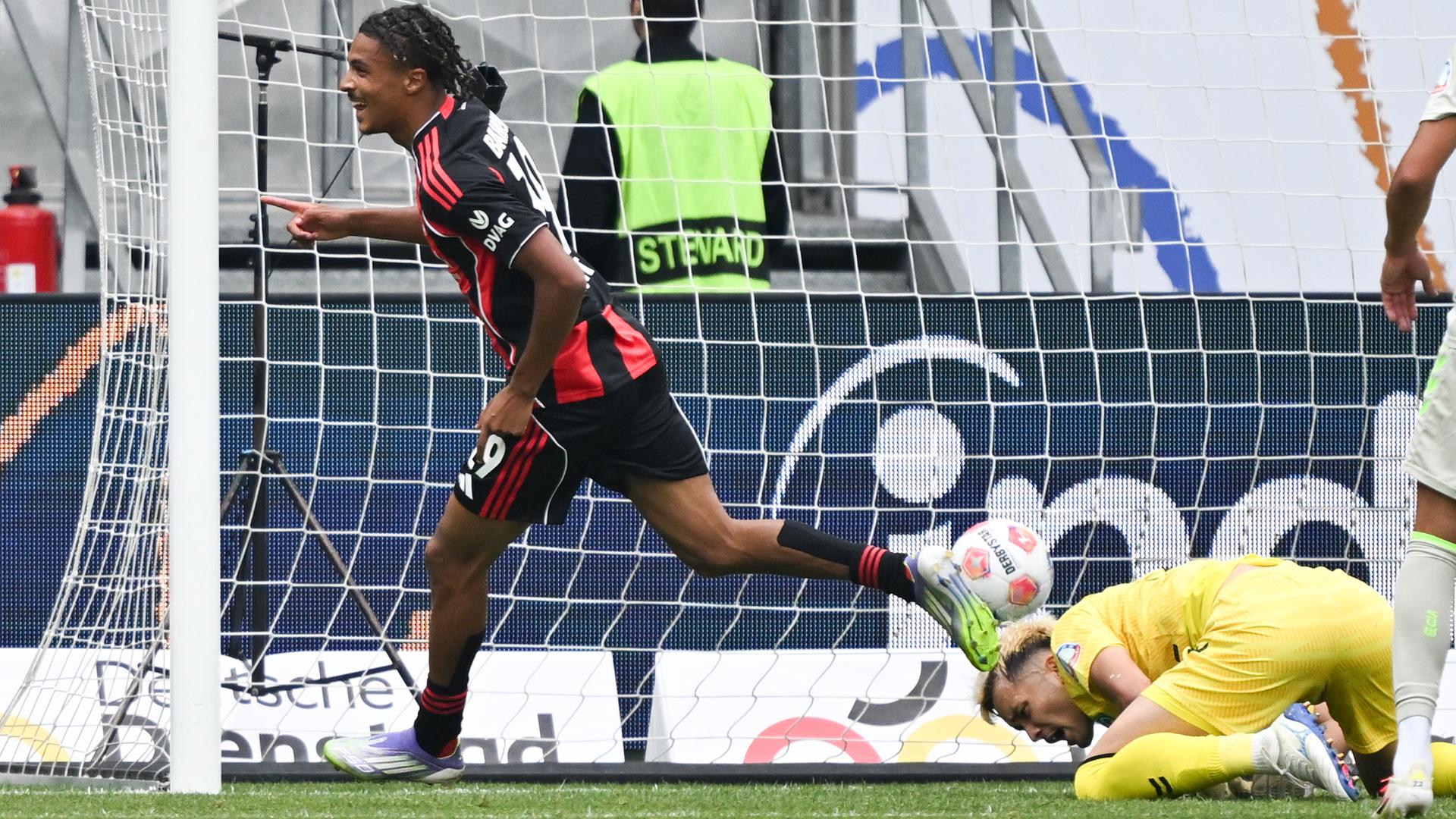 Das Bild zeigt einen Fußball-Spieler beim Torjubel und einen am Boden liegenden Torwart.