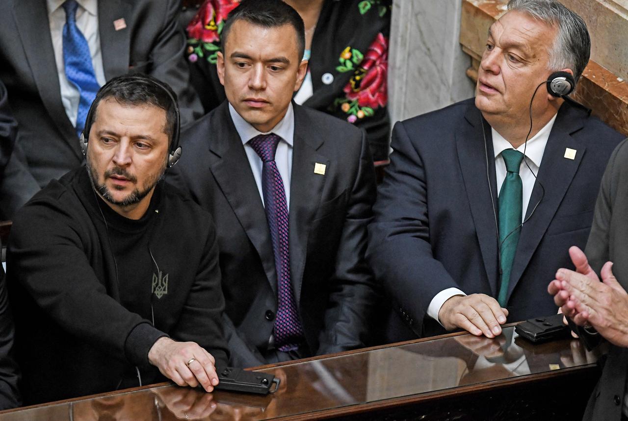 Der ukrainische Präsident Selenskyj sitzt im Parlament in Buenos Aires an einem Tisch, neben ihm anderem Ungarns Ministerpräsident Orban.